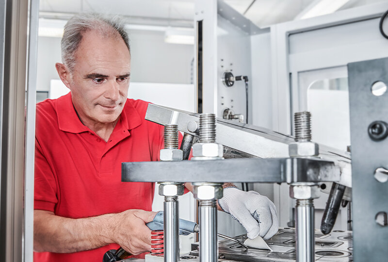 Production worker in front of a big molding press