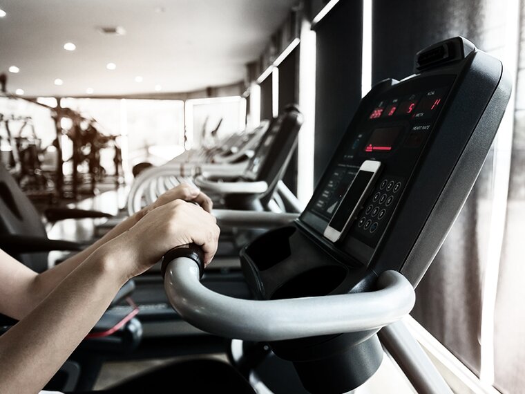 close-up of two human hands at the control panel of an indoor sports equipment